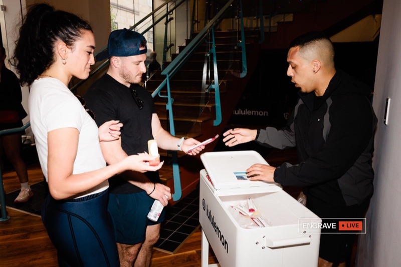 Guests collect freshly engraved pieces at an Engrave Live station at a brand event.
