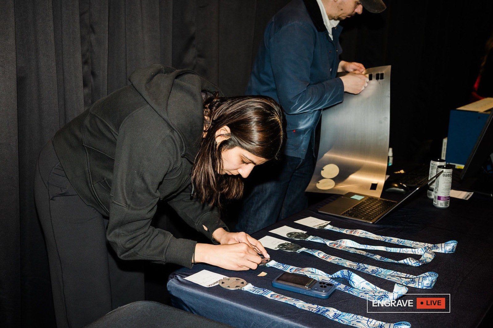 An engraver personalising finisher medals at the event table.