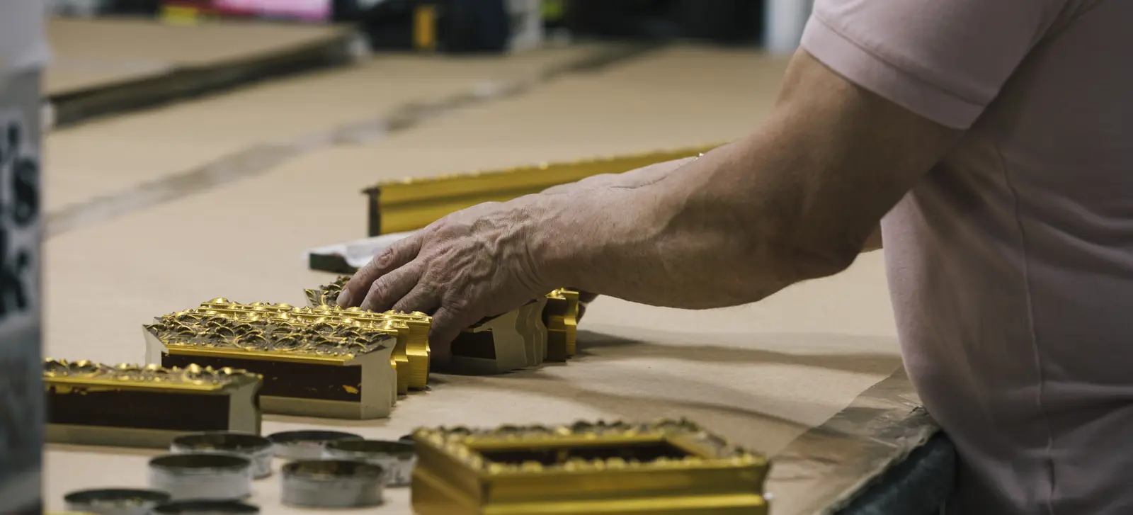 A framer’s hands at the bench, laying out gilded frame corners at Frame Chicago.